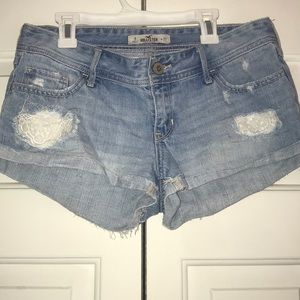 Light wash jean shorts with lace design.